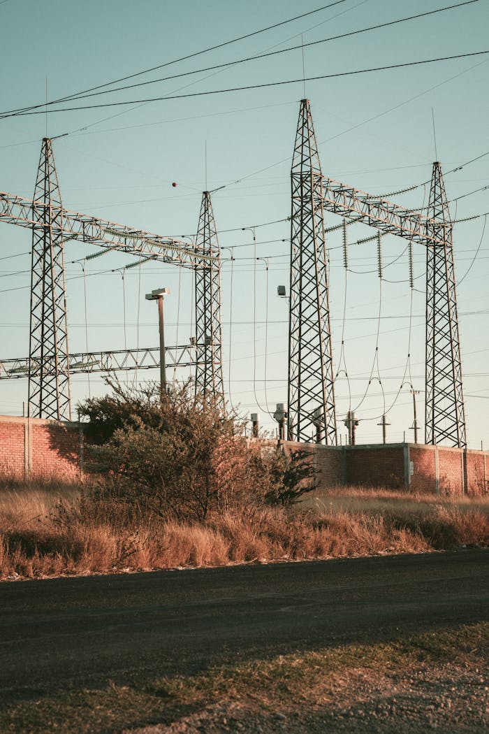 Rustic open field showcasing a high voltage electrical substation during daytime.